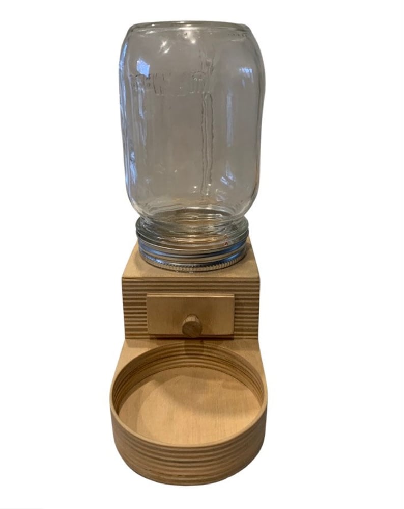 Peut inclure: Un distributeur de nourriture pour animaux en bois avec un bocal en verre pour la nourriture s&egrave;che et un bol pour l'eau. Le distributeur a un petit tiroir pour ranger les friandises.