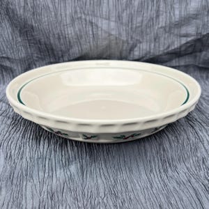 May include: Off-white ceramic pie dish with a green rim and holly berry design. The dish has a fluted edge and is suitable for baking and serving. A festive addition to any kitchen.
