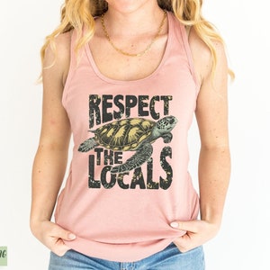 May include: A pink tank top with a graphic of a sea turtle and the text "Respect the Locals".