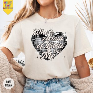 a woman wearing a white t - shirt with a heart on it