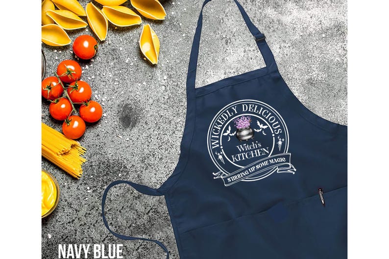 May include: Navy blue kitchen apron with a white design that says "Wickedly Delicious Witch's Kitchen Stirring Up Some Magic".