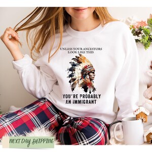 a woman wearing a white sweatshirt with an indian headdress