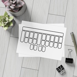 May include: A black and white keyboard-shaped sticker sheet on a white background. The sticker sheet has a rectangular top with several rectangular and square keys. Two small succulent plants and office supplies are also in the image.