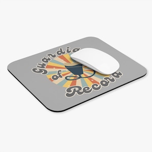 Puede incluir: Una alfombrilla de ratón gris con un diseño retro que presenta el texto "Guardian of Record" en una fuente estilizada. El diseño incluye un gráfico de una copa de cóctel y un patrón de rayos de sol en tonos naranja, amarillo y azul. Un ratón de ordenador blanco descansa sobre la alfombrilla.