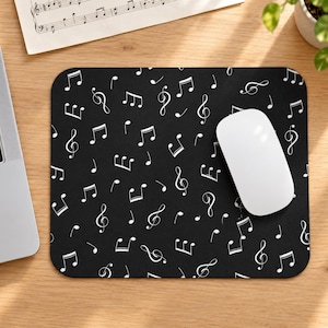 May include: A rectangular mouse pad featuring a black background with a repeating pattern of white musical notes, including treble clefs, eighth notes, and quarter notes, arranged across the entire surface of the mat.