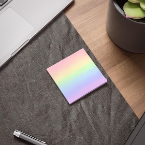 May include: A square sticky note featuring a horizontal gradient design that transitions through soft pastel shades of yellow, green, blue, and purple. The paper pad is positioned flat, displaying a smooth surface with clean, straight edges.