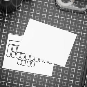 Könnte beinhalten: Draufsicht auf einen Arbeitsplatz mit einer schwarz-weißen Schneidematte. Auf der Matte liegen zwei weiße rechteckige Karten, eine davon mit einer schwarzen Tastaturumriss. Ein schwarzer Bleistift, ein Klebebandabroller und eine Klebebandrolle sind ebenfalls zu sehen.
