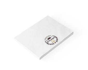 May include: White notepad with the text "World's Best Paralegal" in a black circle with a gold crown and scales of justice.
