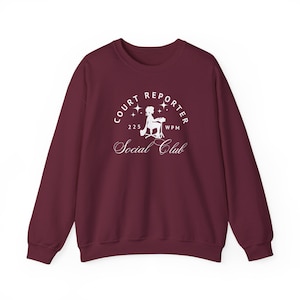 May include: A maroon sweatshirt with a white graphic that reads "Court Reporter Social Club" with an illustration of a person typing and the text "225 WPM". The sweatshirt has long sleeves and a crew neck.