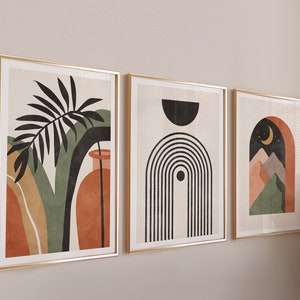 May include: Three framed abstract art prints with gold frames. The first print features a green and orange abstract design with a black palm leaf and a vase. The second print features a black and white abstract design with a rainbow and a circle. The third print features a green, orange, and brown abstract design with a crescent moon and mountains.