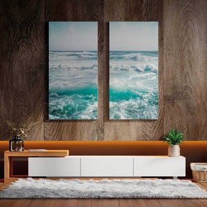 May include: A modern living room with a wooden accent wall and a white entertainment center. Two framed ocean wave prints hang above the center. A fluffy gray rug and a potted plant add to the room's decor. Decorative lighting and shelving complete the space.