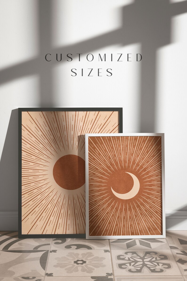 May include: Two framed prints with a sun and moon design. The sun print is in a black frame and the moon print is in a white frame. Both prints have a brown background with orange sun and moon shapes.
