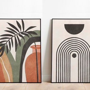 May include: Two framed abstract art prints in a minimalist style. The print on the left features a black and green palm leaf with a terracotta vase. The print on the right features a black and white geometric design with a half circle and a rainbow.