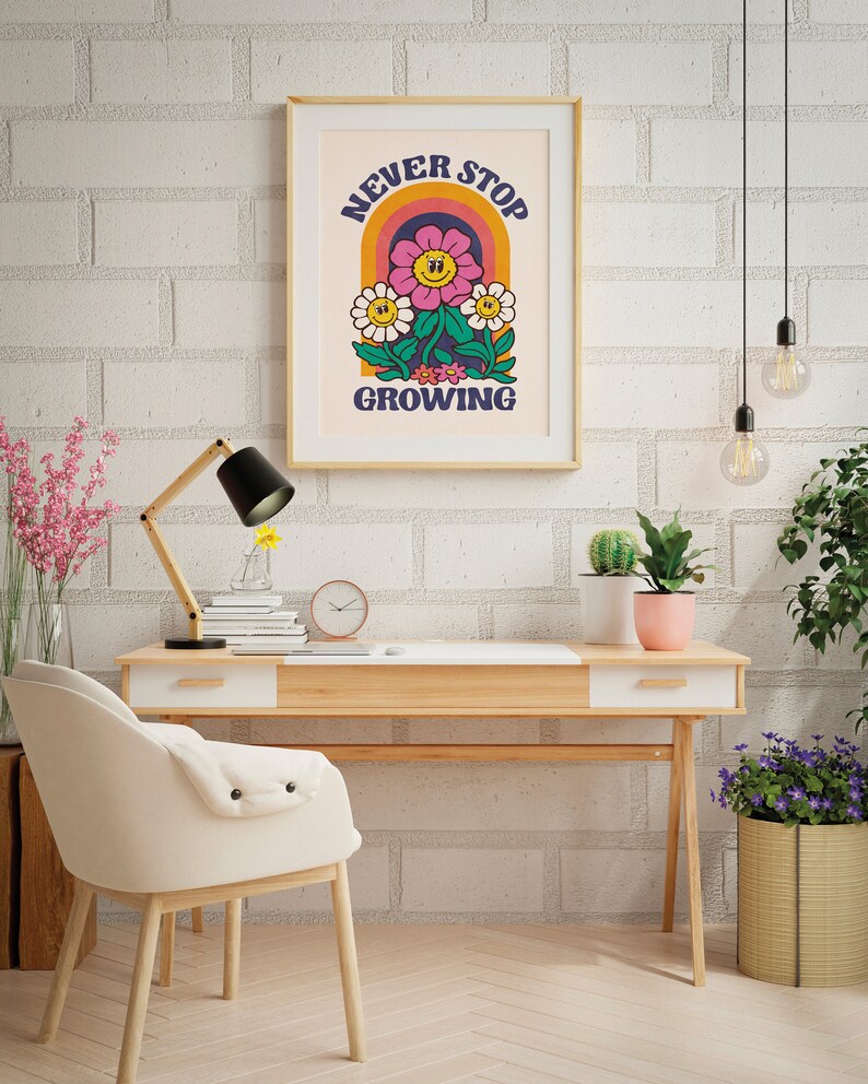 May include: A framed print with a retro-style illustration of a flower with a smiling face. The flower is surrounded by a rainbow arch and the text "NEVER STOP GROWING".