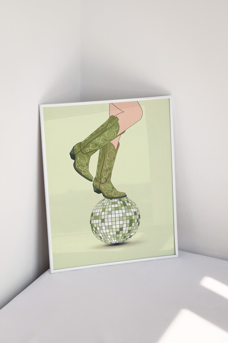 Pode incluir: Um par de botas de cowboy verdes com bordados florais em cima de uma bola de discoteca prateada sobre um fundo verde claro.