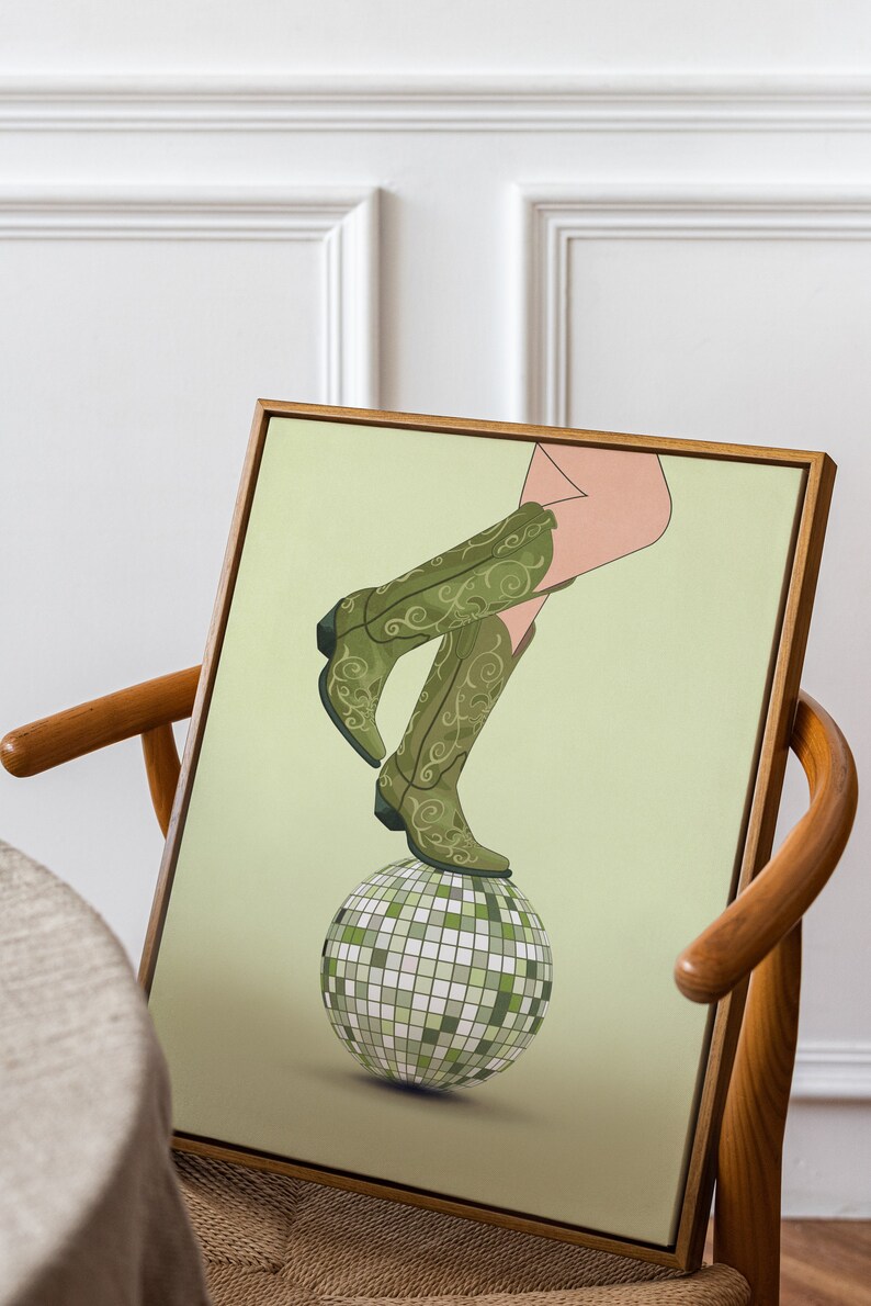 Pode incluir: Uma bota de cowboy verde e dourada com padr&atilde;o, equilibrada em cima de uma bola de discoteca prateada sobre um fundo verde claro.