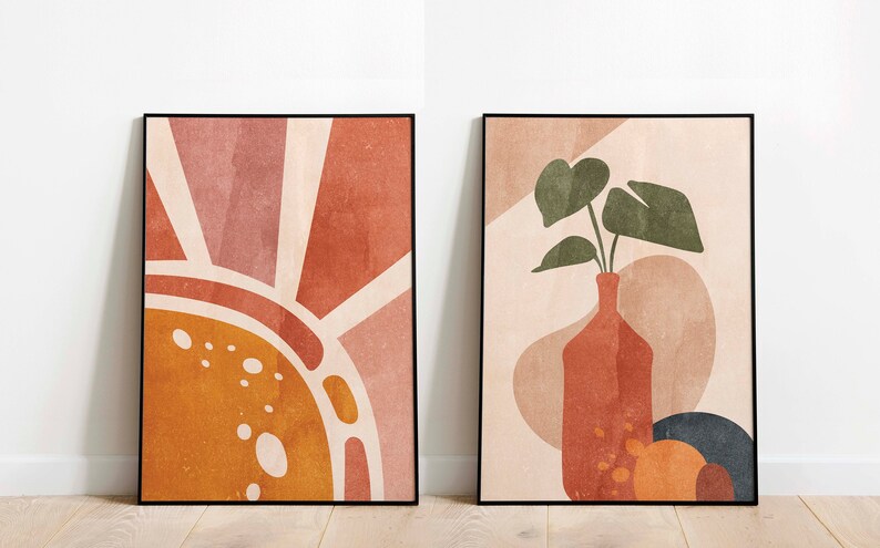 K&ouml;nnte beinhalten: Zwei gerahmte abstrakte Kunstdrucke im minimalistischen Stil. Der erste Druck zeigt eine stilisierte Sonne in Orange-, Gelb- und Rosat&ouml;nen. Der zweite Druck zeigt eine Vase mit einer Blattpflanze in Gr&uuml;n-, Braun- und Beiget&ouml;nen.