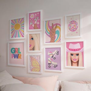 May include: A collection of framed wall art with a retro theme. The art features a variety of designs, including a sunburst, a peace sign, roller skates, a disco ball, and a Barbie portrait. The color palette includes pink, yellow, and blue.