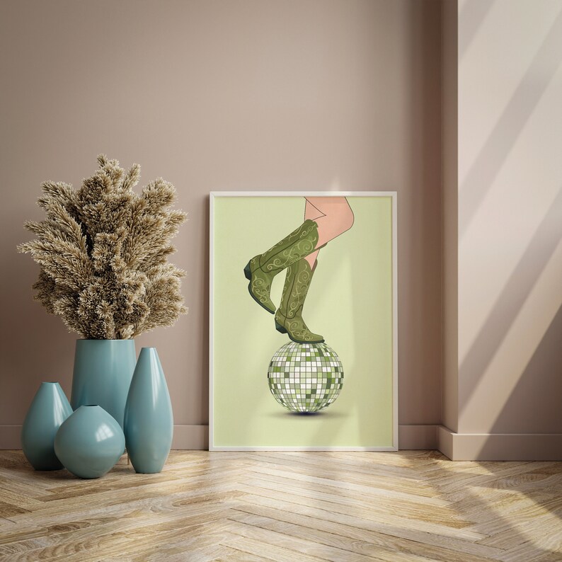 Pode incluir: Uma bota de cowboy verde e marrom com bico fino est&aacute; em cima de uma bola de discoteca prateada. A bota est&aacute; em um fundo verde claro.