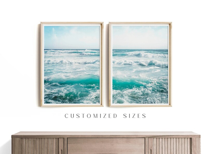 May include: Two framed prints of ocean waves in shades of turquoise and white. The prints are displayed side-by-side, with a light blue sky visible above the waves. The frames are a light wood color. Text at the bottom reads "CUSTOMIZED SIZES".