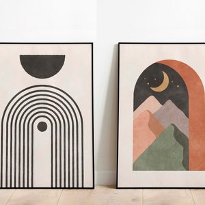 May include: Two framed abstract art prints in a minimalist style. The print on the left features black and white geometric shapes, including a half circle and a series of vertical lines. The print on the right features a landscape scene with a crescent moon, stars, and mountains in shades of pink, green, and brown.