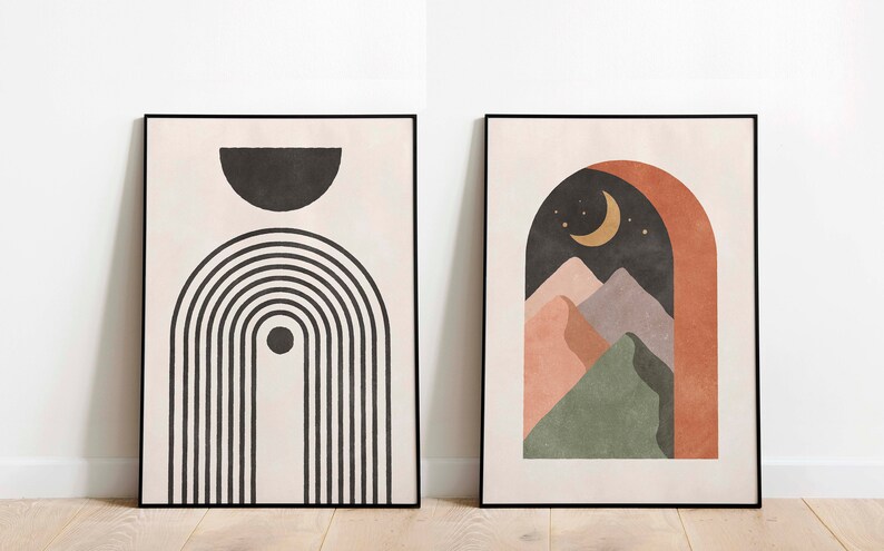 May include: Two framed abstract art prints in a minimalist style. The print on the left features black and white geometric shapes, including a half circle and a series of vertical lines. The print on the right features a landscape scene with a crescent moon, stars, and mountains in shades of pink, green, and brown.