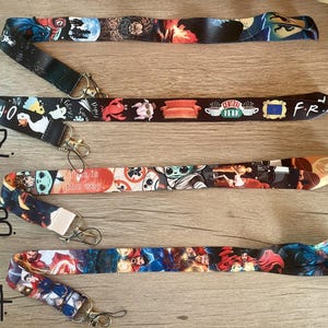 May include: Ten colorful lanyards with different designs, including a Stranger Things design, a Friends design, a Baby Yoda design, and a Marvel design. The lanyards are numbered 11 through 14.