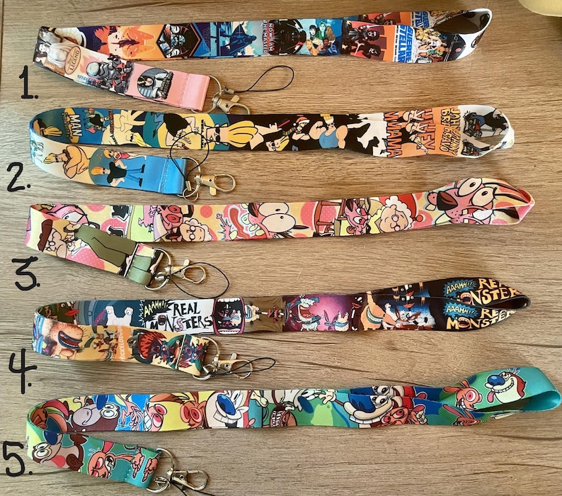 May include: Five colorful lanyards with cartoon characters printed on them. The lanyards are numbered 1 through 5. The characters include Dexter's Laboratory, Johnny Bravo, Courage the Cowardly Dog, and the Powerpuff Girls.