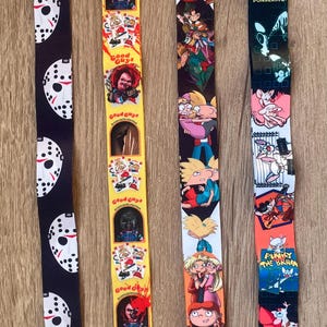 May include: Four different colorful lanyards with various cartoon characters and text. The lanyards are yellow, black, orange, and blue. The text on the lanyards includes "Good Guys", "Pinky and the Brain", and "Take Over the World".