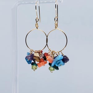 May include: Gold hoop earrings with a cluster of colorful gemstone charms, including turquoise, coral, and amethyst.