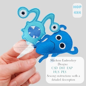 May include: Two blue felt monster-like shapes with white and black eye details. One has a spiky body and a mouth with white teeth. The other has tentacles. The image includes text that says "Machine Embroidery Designs" and "Sewing instructions with a detailed description."