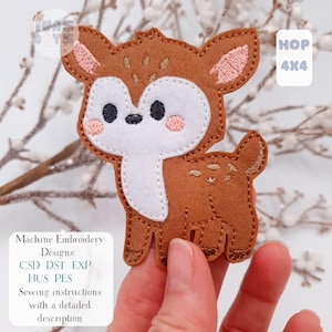May include: A brown felt deer applique with a white face, pink cheeks, and black eyes. The applique has the text "HOP 4X4" and "Machine Embroidery Designs" with file types listed. Sewing instructions with a detailed description are also included.