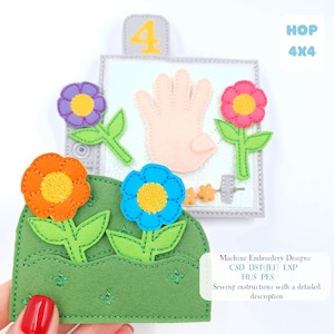 May include: A felt craft with a garden theme, including colorful flowers, a hand, and the number 4. The flowers are orange, blue, purple, and pink with yellow centres. The background is light blue with the text "HOP 4X4". The image also includes text about machine embroidery designs and sewing instructions.