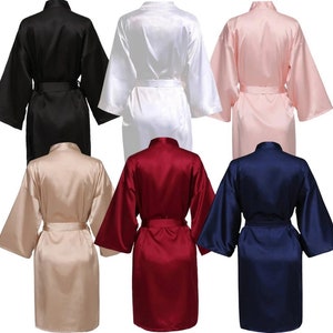 May include: Six satin robes in different colours: black, white, pink, beige, burgundy, and navy blue. The robes have long sleeves, a shawl collar, and a tie belt.