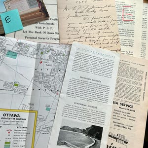 May include: A collection of vintage ephemera, including a map of Ottawa, handwritten letters, and brochures. The items are arranged on a wooden surface, with a blue sticky note labeled "E" visible.