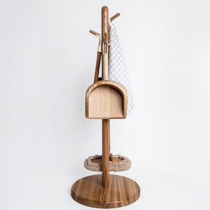 Può includere: Un supporto in legno per un set di pulizia con base rotonda, palo centrale e parte superiore curva. È dotato di paletta, spazzola, piccolo asciugamano e tampone per la pulizia circolare. Il supporto è in legno chiaro.