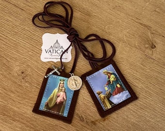 May include: A religious scapular with two rectangular fabric pendants featuring religious imagery. The pendants are connected by a brown cord. One pendant shows Mary and Jesus, the other shows a religious scene. A small cross and a medal are attached.