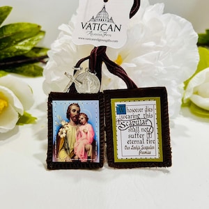 Può includere: Uno scapolare religioso con due pendenti rettangolari. Uno presenta un'immagine di San Giuseppe e Gesù bambino, l'altro ha il testo: "Whosoever dies wearing this Scapular shall not suffer eternal fire". Un'etichetta con il logo Vatican Religious Gifts è allegata.