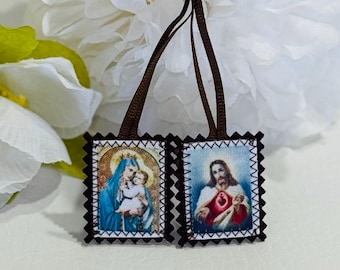 May include: Two small, framed religious images with brown borders. The image on the left depicts the Virgin Mary holding baby Jesus. The image on the right depicts Jesus with his heart exposed. Both images have a white background and are surrounded by a black border with a white trim.