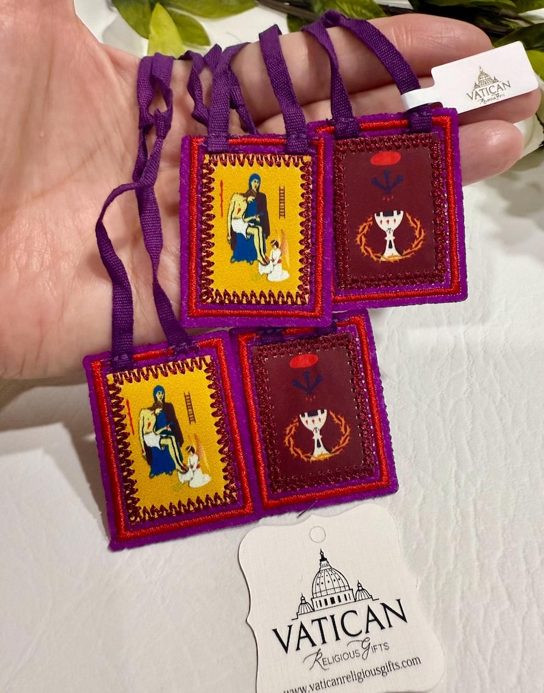 May include: A collection of small, embroidered religious items with purple straps. The items feature images of religious figures and symbols in yellow and burgundy. The tag reads "VATICAN Religious Gifts".