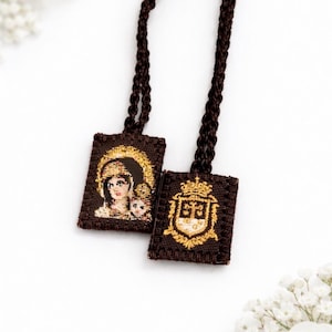 May include: Two brown woven pendants with detailed religious imagery. One features a depiction of a woman and child, the other a gold crest. Each pendant is attached to a brown cord.