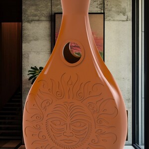 May include: A terracotta vase with a carved sun design. The vase has a round opening in the middle and a wide base.