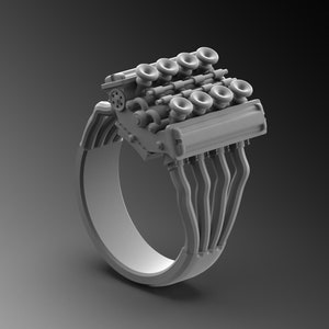 Puede incluir: Un anillo de plata con un diseño de motor detallado. El anillo presenta un bloque de motor estilizado con múltiples cilindros y colectores de admisión.