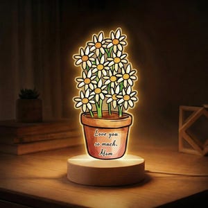 May include: A white ceramic mug with a black handle and the text "But First, Coffee" in a black, handwritten-style font. The mug is on a white surface.