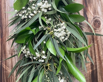 May include: A long garland of green eucalyptus leaves and small white baby's breath flowers.