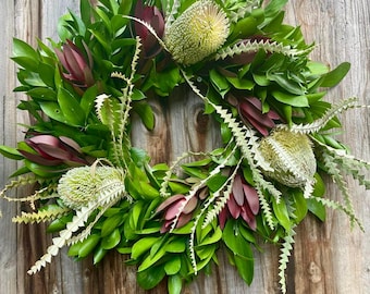 May include: A green wreath with red and white flowers. The wreath is made of leaves and branches.