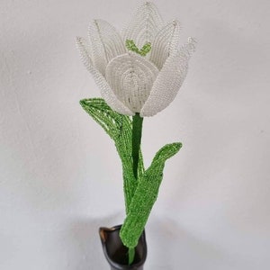 May include: A white beaded tulip with green beaded leaves in a black vase.