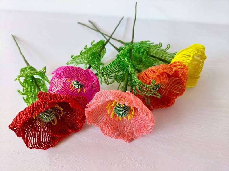 K&ouml;nnte beinhalten: Ein Strau&szlig; aus f&uuml;nf Perlenblumen mit gr&uuml;nen Stielen. Die Blumen sind rot, rosa, orange und gelb.