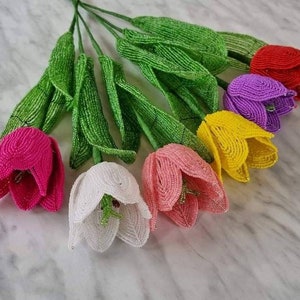May include: A bouquet of beaded tulips in various colors, including pink, white, yellow, purple, and red. The tulips are handmade and have green beaded stems.