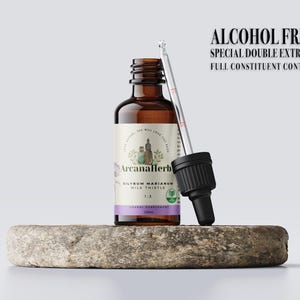 May include: A brown glass bottle with a dropper, labelled "Silybum Marianum Milk Thistle 1:3" and "ArcanaHerb". The bottle is on a grey stone surface. The label also says "Alcohol Free, Special Double Extract, Full Constituent Content".